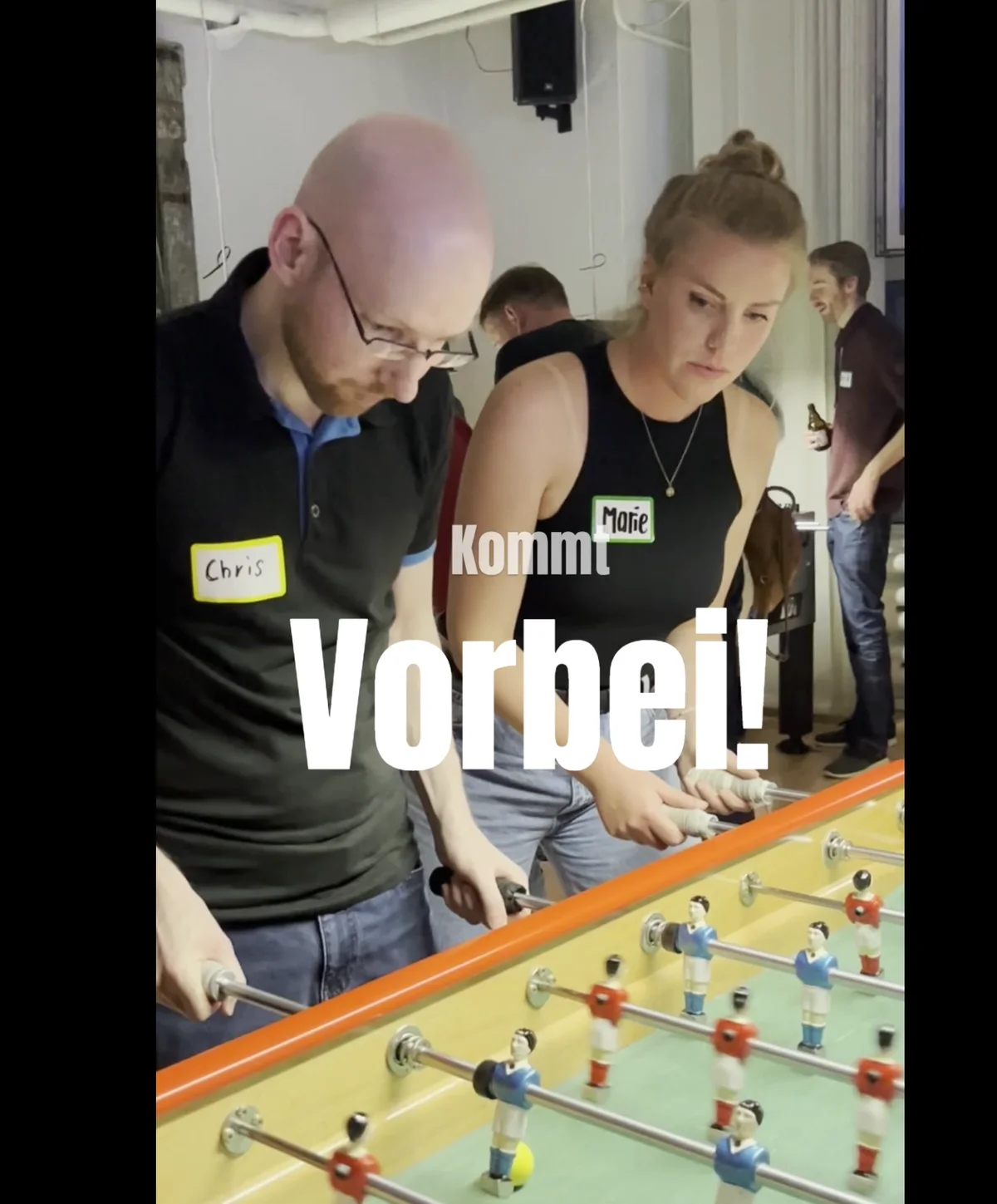 Videoausschnitt mit zwei Gästen beim Spielen am orangefarbenen Tisch